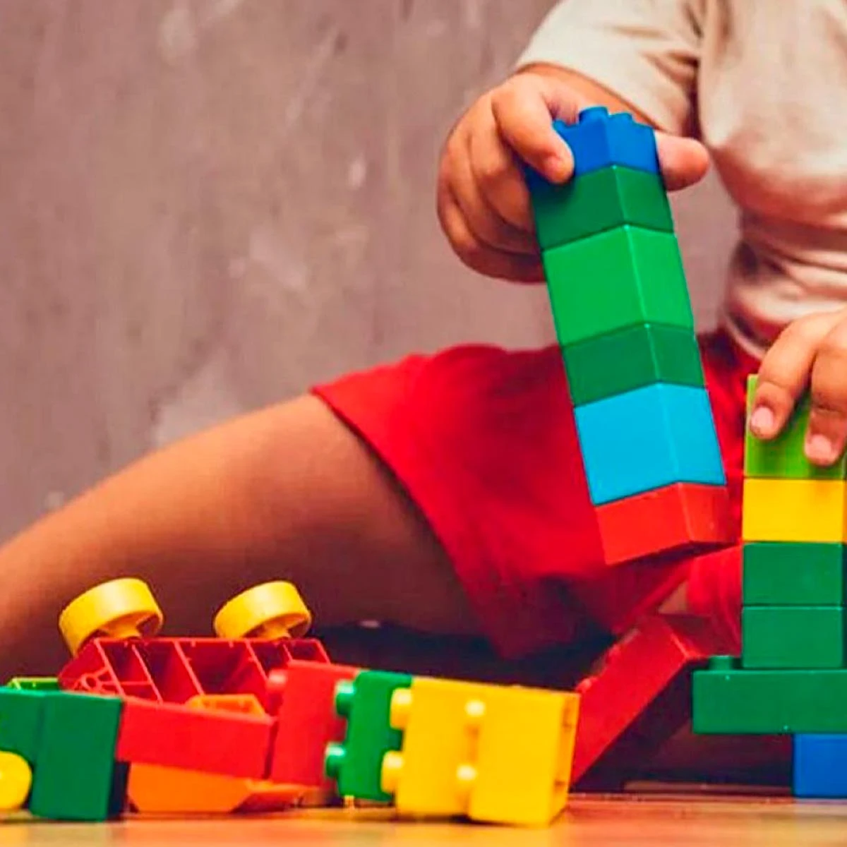 Niño jugando con coloridos bloques de construcción en el suelo.