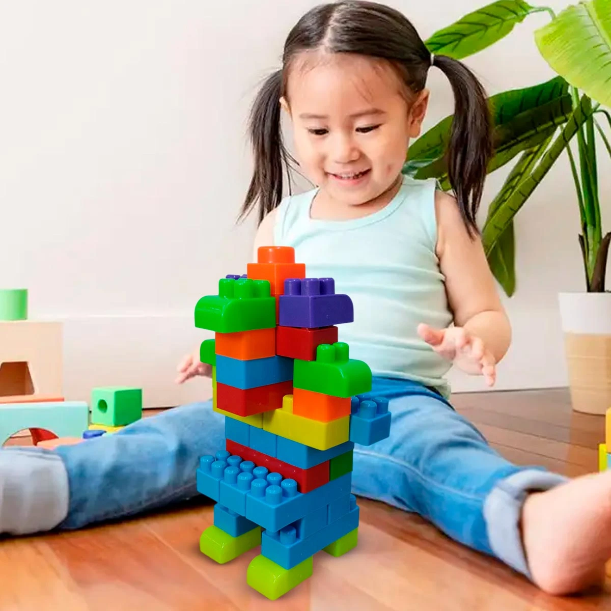 Niña jugando con bloques de construcción de colores en el suelo.