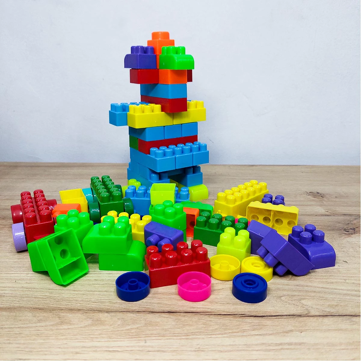 Bloques de construcción de colores apilados y desparramados sobre una mesa.