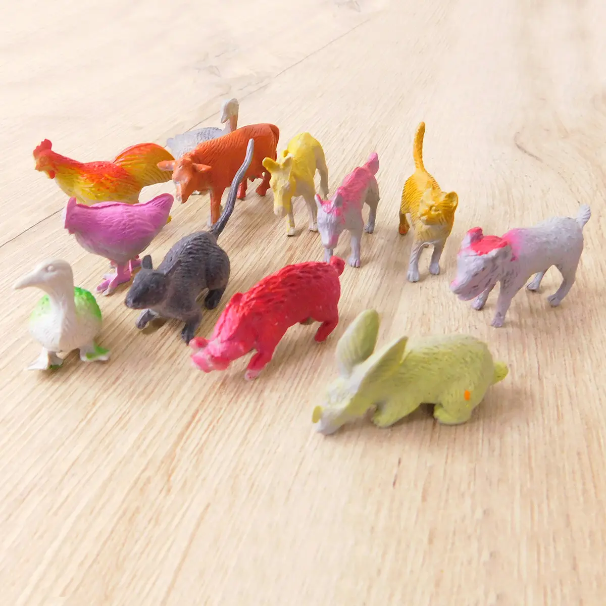 Figuras de animales de granja en plástico sobre superficie de madera.