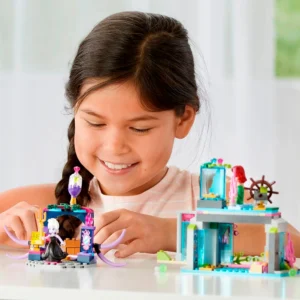 Niña jugando con set de construcción submarino con figuras de sirena y bruja.