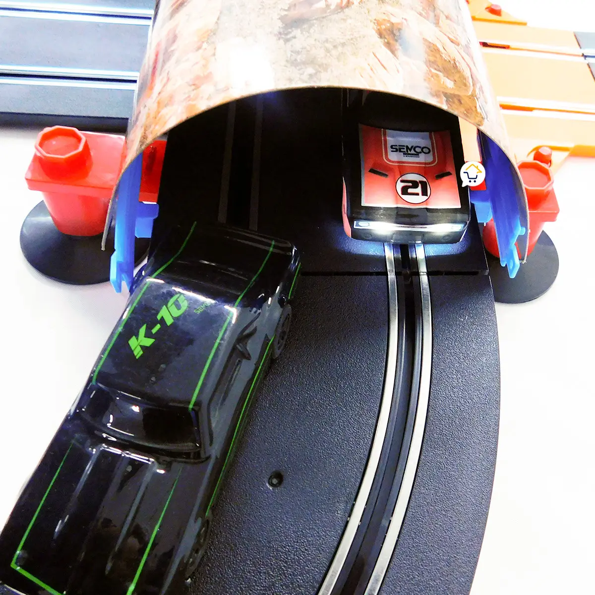 Dos autos de juguete en una pista de carreras, uno rojo y otro negro.