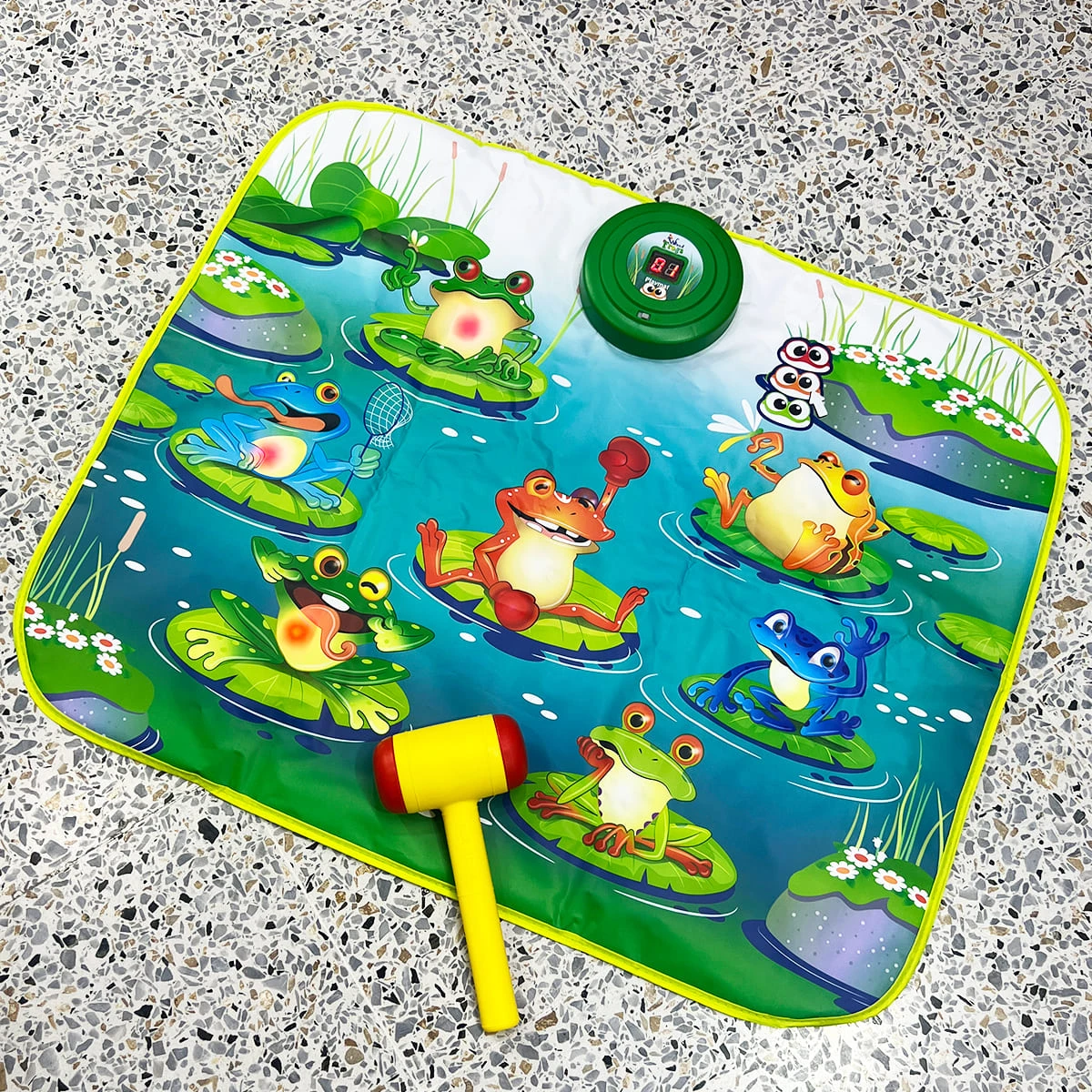 Alfombra de juego interactiva con diseño de sapos y martillo.