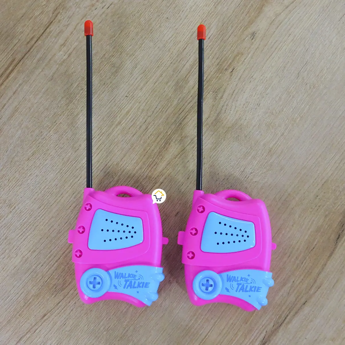 Dos walkie talkies infantiles rosas con antenas negras en una superficie de madera.