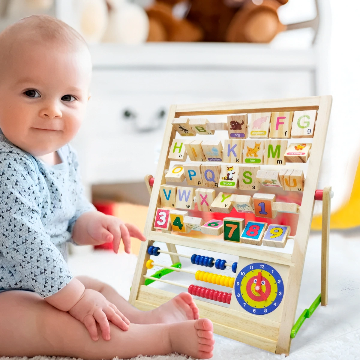 Bebé sentado junto a tablero educativo con letras, números y ábaco.