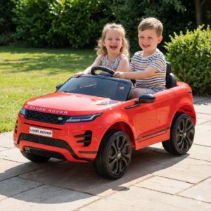 Dos niños sonrientes en un carro eléctrico rojo de juguete Land Rover.