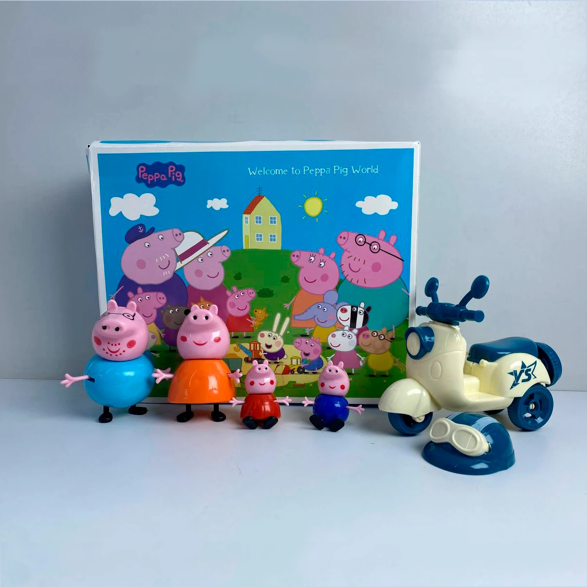 Figuras de Peppa Pig y familia con fondo de caja colorida.