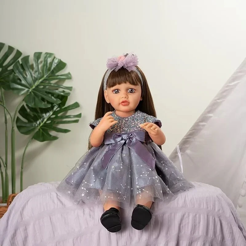 Muñeca realista sentada con vestido brillante y lazo.